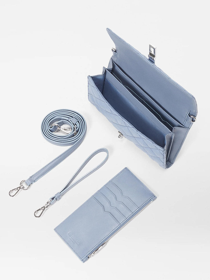 The MZ Wallace Astor Convertible Crossbody in Stone Blue Oxford features a silver clasp, Italian leather strap, detachable crossbody option, wrist strap, and matching cardholder with four slots, beautifully displayed on a white background.