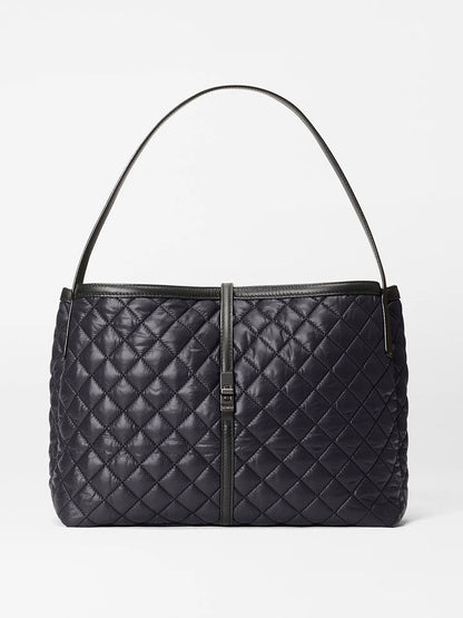 The MZ Wallace Astor East West Tote in Black Oxford features a quilted design, black Italian leather, a single shoulder strap, and a rectangular front clasp, shown against a plain white background.