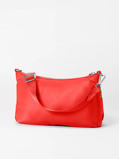 The MZ Wallace Chelsea Petite Shoulder Bag in Bright Cherry Bedford is a small, vibrant red bag with Italian leather trim, short strap, and silver clasps set against a light grey background.