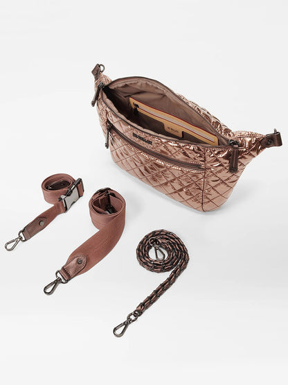 A MZ Wallace Crosby Crossbody Sling Bag in Copper Metallic Lacquer Oxford with its top zipper open is shown, alongside three interchangeable straps: a wide fabric strap, a buckle-attached strap, and a braided strap. This metallic quilted handbag also features elegant Italian leather trim for a hands-free option.