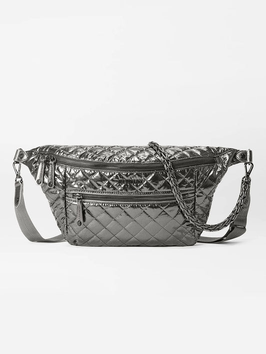 The MZ Wallace Crosby Crossbody Sling Bag in Pewter Metallic Oxford features a gray quilted design with multiple zippers and a braided, adjustable strap against a white background, perfect for hands-free convenience.