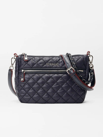 Introducing the MZ Wallace Crosby Ella Crossbody in Black Oxford, a luxurious quilted bag crafted from premium Italian leather. It features silver hardware and striking red accents, along with a front zipper and an adjustable strap for exceptional versatility.