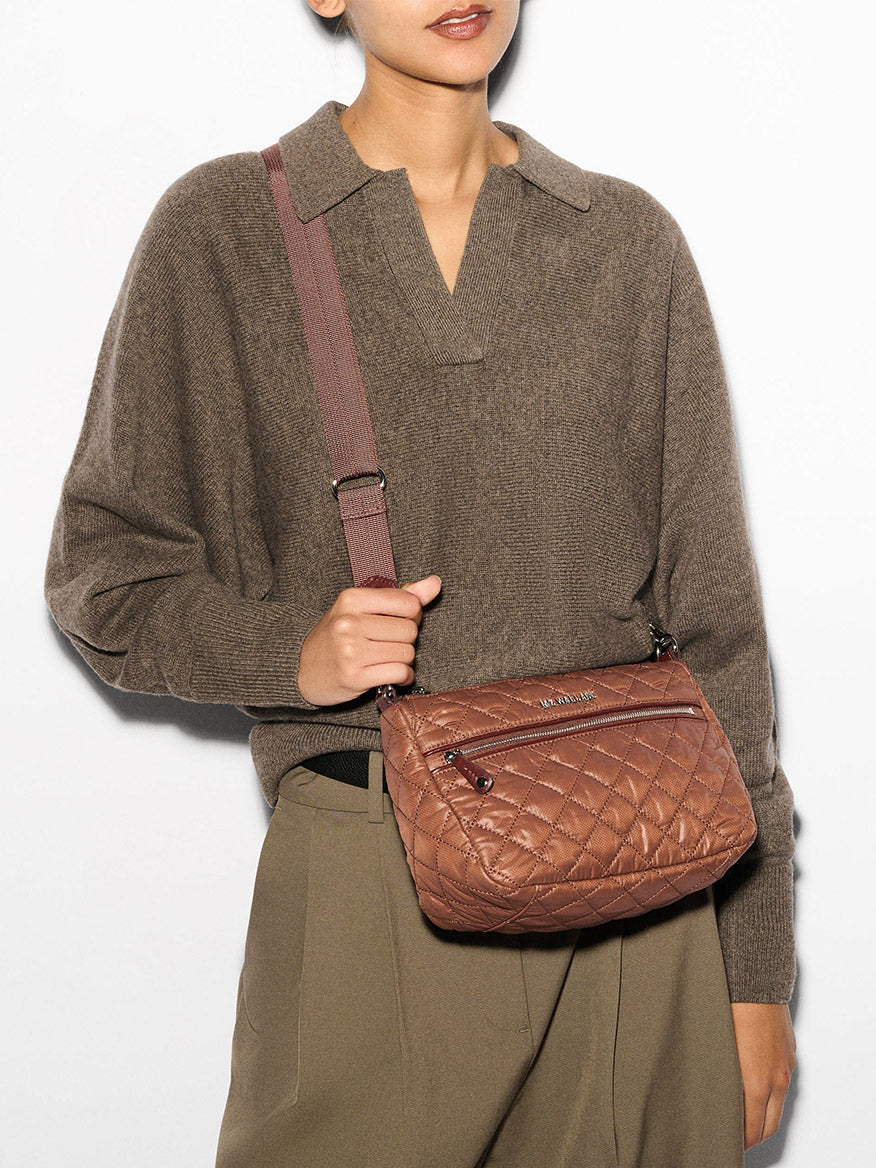 A person wearing a brown sweater and tan pants is carrying an MZ Wallace Crosby Ella Crossbody in Terracotta Oxford.