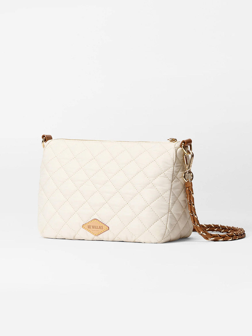 The MZ Wallace Crosby Ella Crossbody in Sandshell Oxford with Brown features quilted nylon in a cream hue, a gold and brown chain strap, Italian leather trim, and a front leather tag.