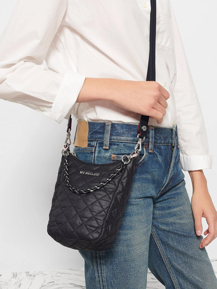 Person wearing a white shirt and blue jeans with an MZ Wallace Crosby Go in Black Oxford tote bag featuring an adjustable strap.