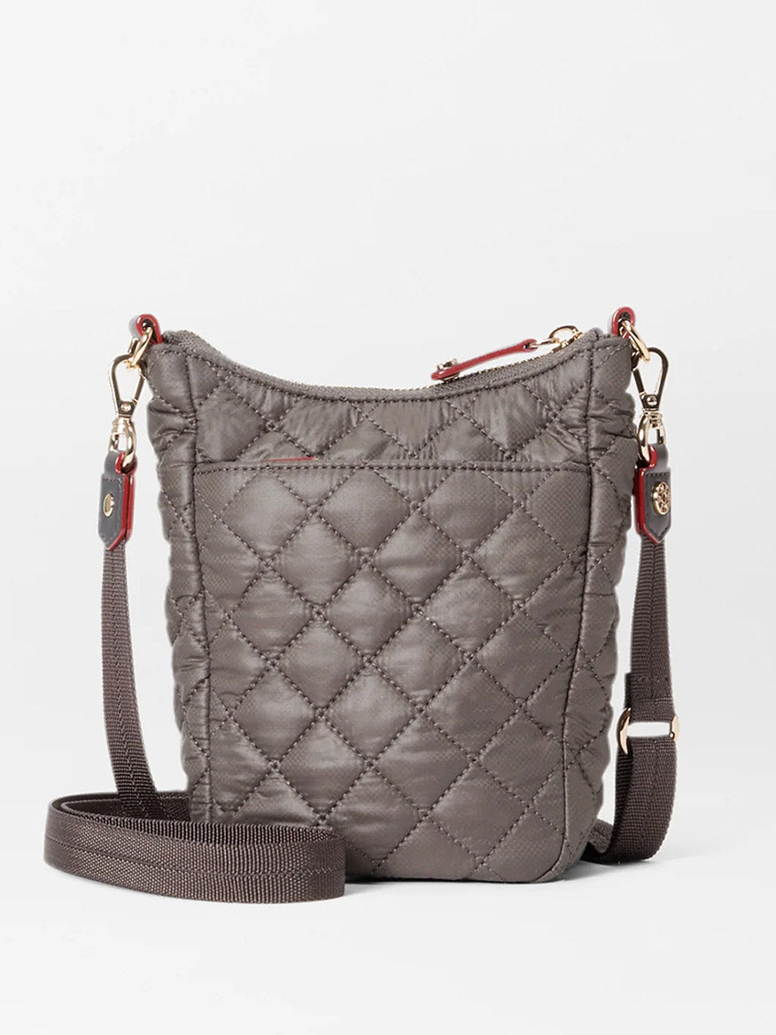 A small, quilted fabric bag in gray featuring a long adjustable crossbody strap, gold hardware, and a front pocket. The MZ Wallace Crosby Go in Magnet Oxford.