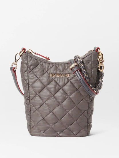 A gray, quilted fabric bag with gold-tone hardware, a detachable chain and leather strap, and a zipper closure. The stylish tote features Italian leather trim and the brand name "MZ Wallace Crosby Go in Magnet Oxford" embossed on the front.