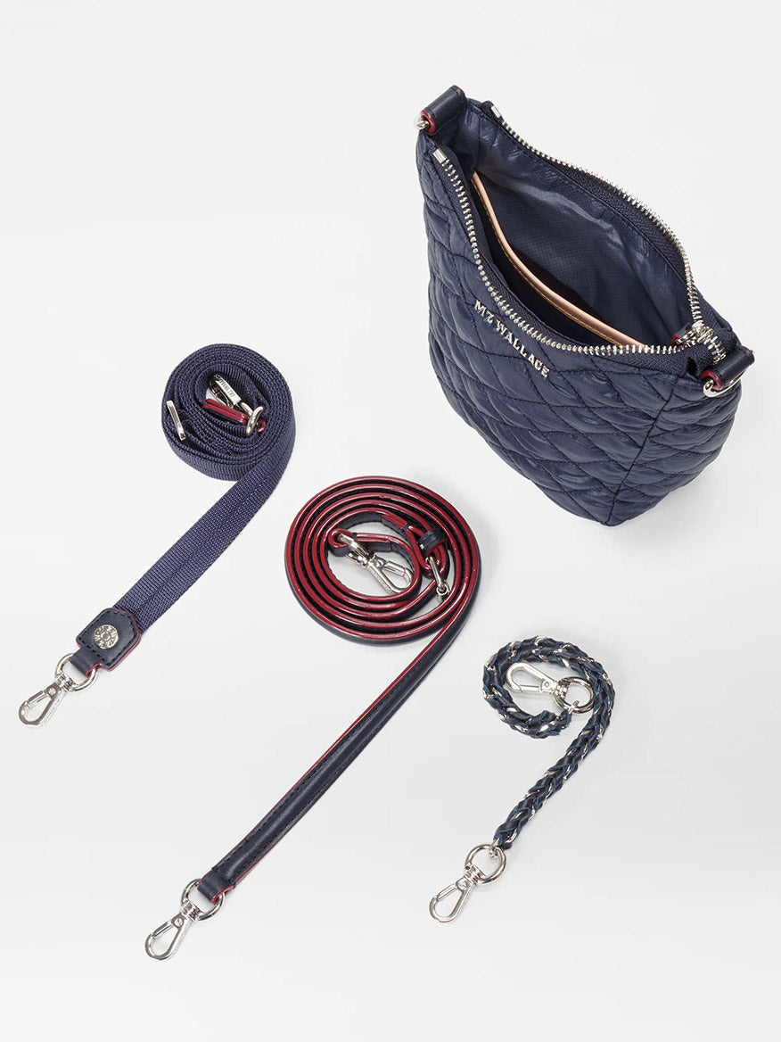 A MZ Wallace Crosby Go in Dawn Oxford with a silver zipper, featuring Italian leather trim, and accompanied by three interchangeable straps: one solid red, one braided blue, and one dark blue with red edges. All straps have metal clasps for easy adjustment.