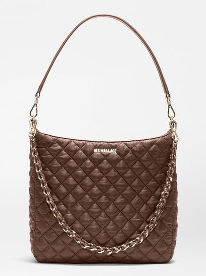 The MZ Wallace Crosby Hobo in Walnut Oxford is a brown quilted handbag with a short shoulder strap and a decorative gold chain, featuring “MZ WALLACE” branding on the front—crafted in the brand’s signature style from premium recycled Oxford nylon for lasting durability.