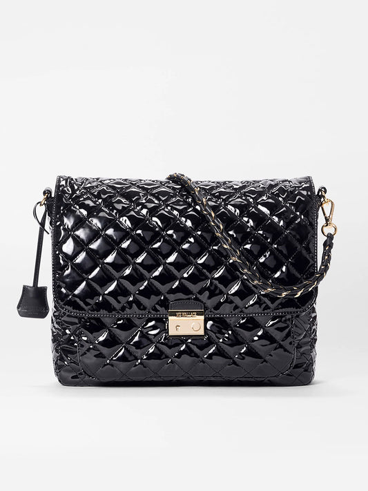 The MZ Wallace Crosby Lock Large Crossbody in Black Lacquer Oxford features quilted patent leather, a gold chain strap, and metal clasp, shown on a plain white background—perfect as an elegant designer bag.