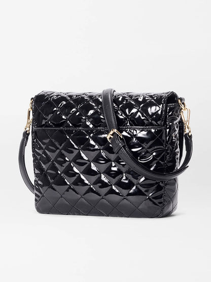The MZ Wallace Crosby Lock Medium Crossbody in Black Lacquer Oxford features quilted patent leather, a gold lock and key closure, and an adjustable strap, shown against a plain white background.