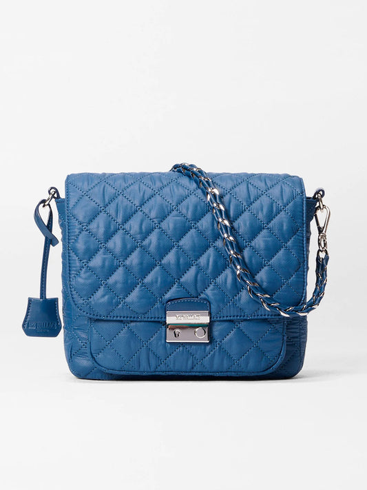 The MZ Wallace Crosby Lock Medium Crossbody in French Blue Oxford features a quilted nylon design with a chain strap and silver clasp, shown here against a plain white background.