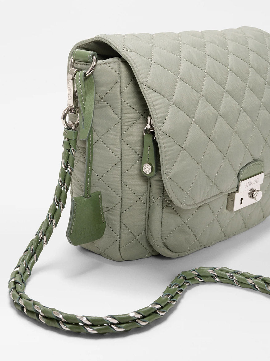 The MZ Wallace Crosby Lock Medium Crossbody in Agave Green Oxford is a quilted nylon handbag with a metal clasp, chain-and-leather strap, and hanging tag, displayed on a plain white background.