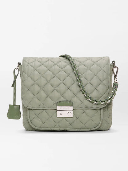 The MZ Wallace Crosby Lock Medium Crossbody in Agave Green Oxford features quilted nylon, a braided strap, front flap with metal clasp, and a small tag—shown on a plain white background.