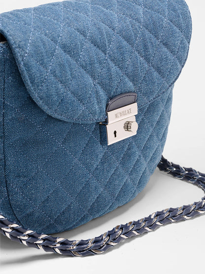 The MZ Wallace Crosby Lock Saddle in True Blue Denim is a quilted denim bag with a silver-tone clasp, Italian leather trim, and a chain-and-leather woven shoulder strap.