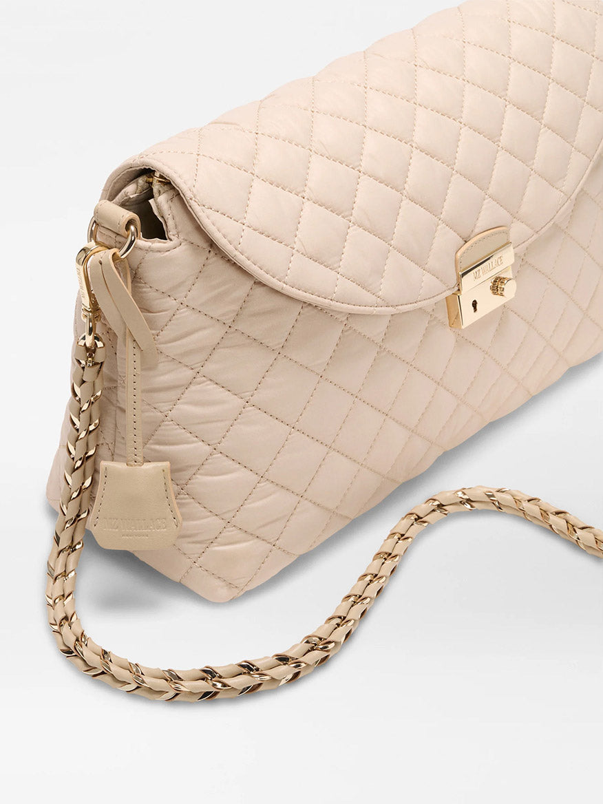 The MZ Wallace Crosby Lock Shoulder in Buff Oxford is a beige quilted Italian leather handbag with a gold clasp, gold-and-leather chain strap, and interchangeable straps for versatile styling, shown on a light background.