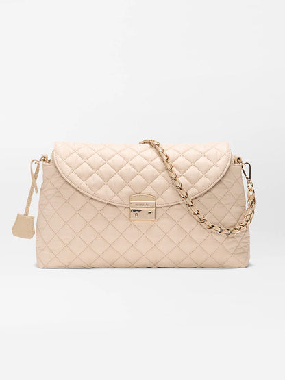 The MZ Wallace Crosby Lock Shoulder in Buff Oxford features beige quilted Italian leather, a gold chain strap, flap closure, and gold-tone clasp, shown against a plain white background.