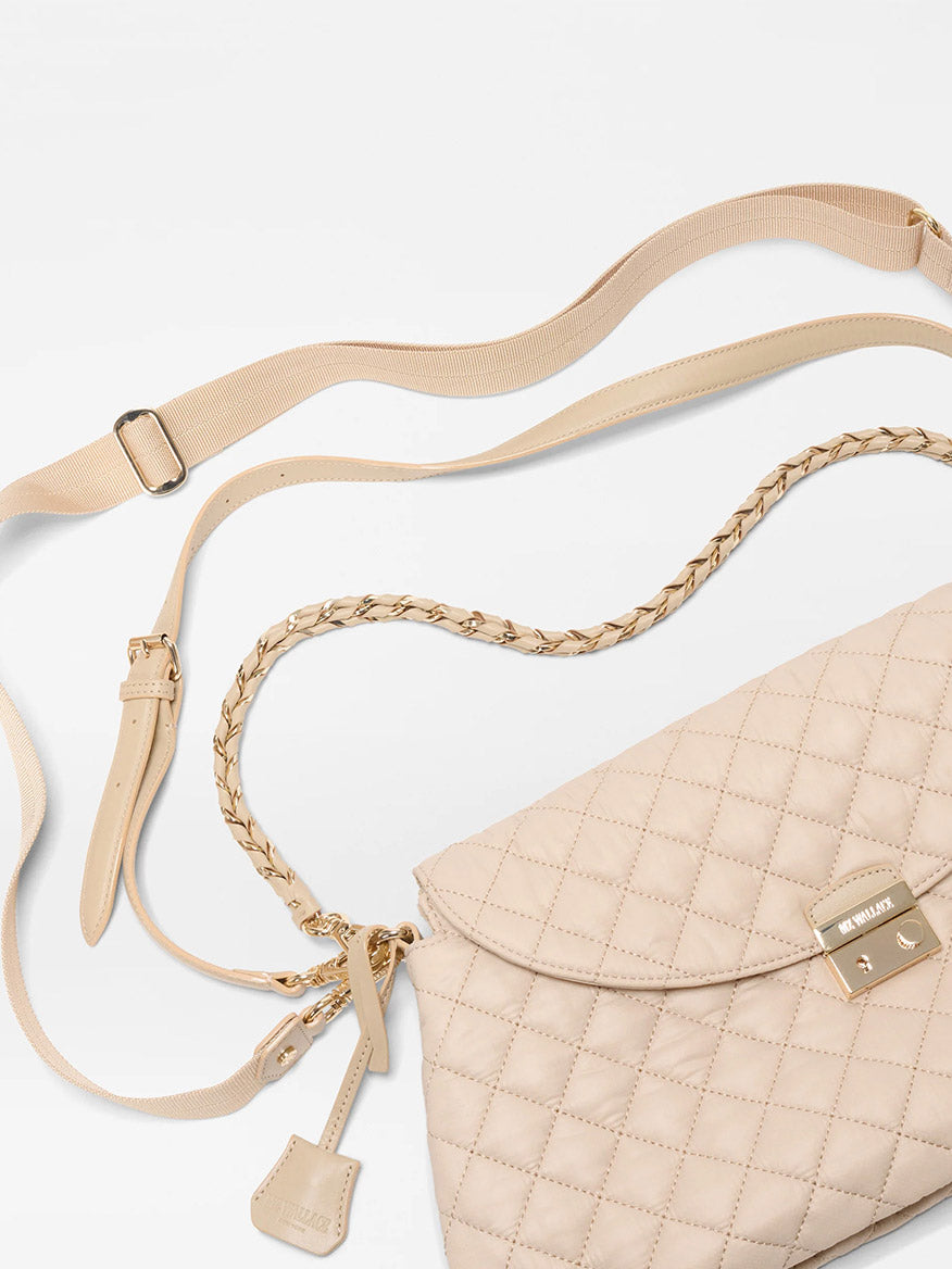 The MZ Wallace Crosby Lock Shoulder in Buff Oxford is a beige quilted Italian leather handbag with gold hardware, interchangeable braided straps, and a luggage tag, shown on a white background.