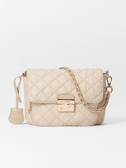 The MZ Wallace Crosby Lock Small Crossbody in Buff Oxford is a quilted designer bag featuring a gold chain strap and clasp, enhanced by elegant Italian leather trim.