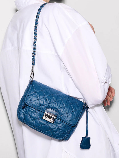 Person wearing a white shirt with an MZ Wallace Crosby Lock Small Crossbody in French Blue Oxford, featuring a silver clasp and a chain-and-leather strap.