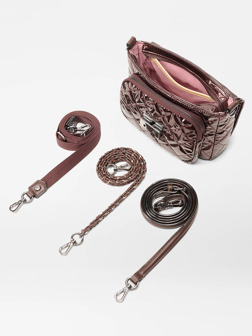 The MZ Wallace Crosby Lock Small Crossbody in Bordeaux Lacquer Oxford is shown, featuring a quilted finish, pink interior, and three detachable straps—solid, braided, and thin leather—each with metal clasps.