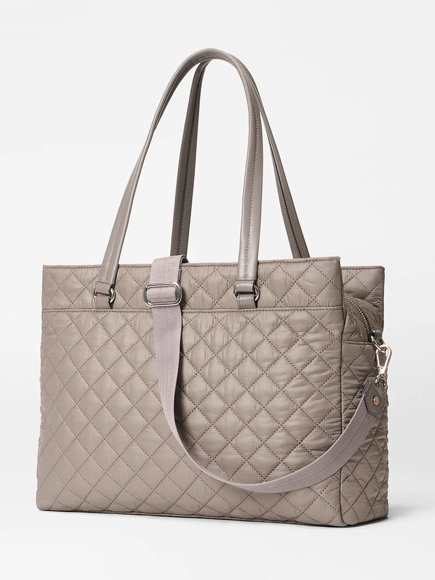 The MZ Wallace Crosby Lock Tote in Morning Dove Oxford is a taupe quilted bag with dual handles, a detachable shoulder strap, zip closure, and minimalist design.