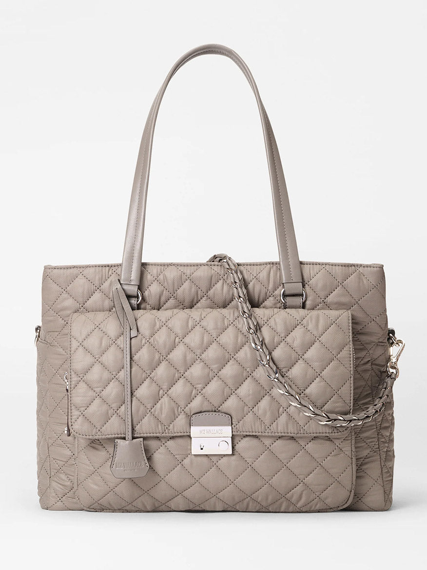 The MZ Wallace Crosby Lock Tote in Morning Dove Oxford features a taupe quilted design, two shoulder straps, a front flap pocket with metal clasp, and a detachable chain strap, shown against a white background.