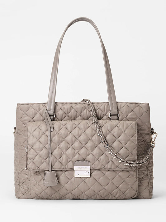 The MZ Wallace Crosby Lock Tote in Morning Dove Oxford features a taupe quilted design, two shoulder straps, a front flap pocket with metal clasp, and a detachable chain strap, shown against a white background.