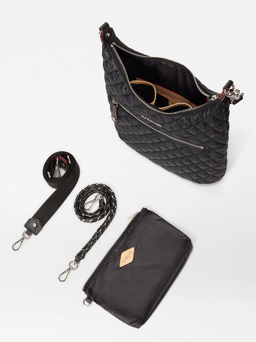 The MZ Wallace Crosby Sienna in Black Oxford handbag, made from Italian leather, includes a shoulder strap, detachable chain strap, braided handle, and a small pouch. The main compartment reveals sunglasses.