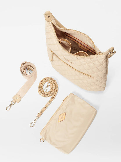 The MZ Wallace Crosby Sienna in Buff Oxford is a cream quilted handbag with detachable straps, luxurious gold hardware, and a matching pouch. It features a beige interior and is crafted from exquisite Italian leather.