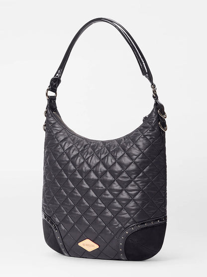 The MZ Wallace Multi Stud Crosby Sienna in Black Stud & Suede is a black quilted leather shoulder bag with Italian suede trim, single handle, curved top, metal studs on the corners, and a gold-tone brand plate on the front.