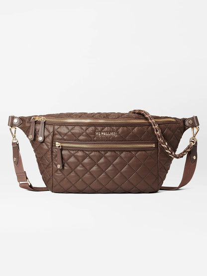 The MZ Wallace Crosby Crossbody Sling Bag in Walnut Oxford is a brown quilted sling bag featuring gold zippers, a braided strap, multiple compartments, and the brand name "MZ WALLACE" stitched on the front, perfect for a hands-free experience.