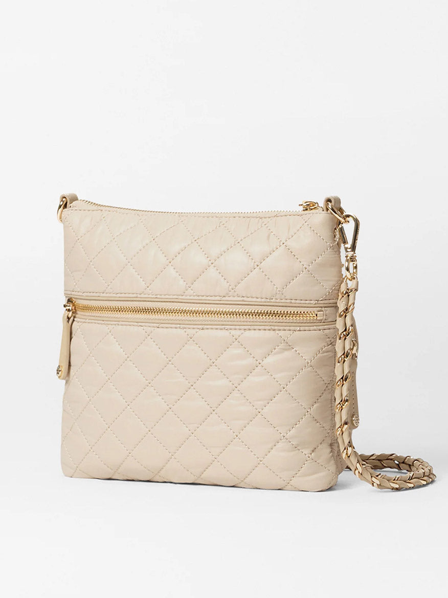 The MZ Wallace Downtown Crosby in Buff Oxford is a sophisticated beige quilted crossbody bag made from luxurious Italian leather, complete with an adjustable chain strap and a handy front zipper pocket.