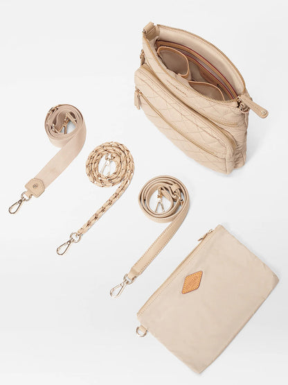 The MZ Wallace Downtown Crosby in Buff Oxford is a beige quilted crossbody bag made from Italian leather, featuring an open top, three detachable straps, and a matching pouch on a white background.