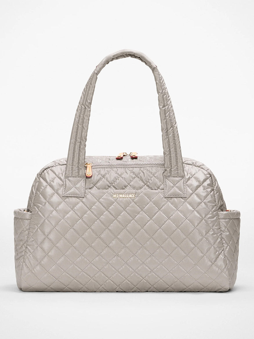 The MZ Wallace Jimmy Deluxe in Sable Pearl Metallic is a light gray quilted handbag with double handles, Italian leather trim, side pockets, and gold-tone zipper and logo, shown against a plain white background.