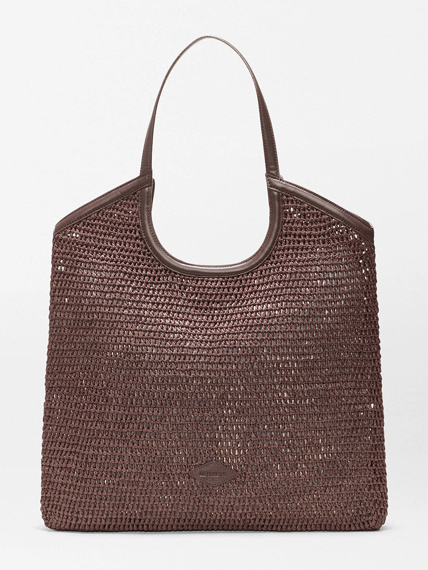 The MZ Wallace Large Crochet Georgica Tote features brown crochet, two handles, gold hardware, and Italian leather trim at the top, displayed against a plain light background.