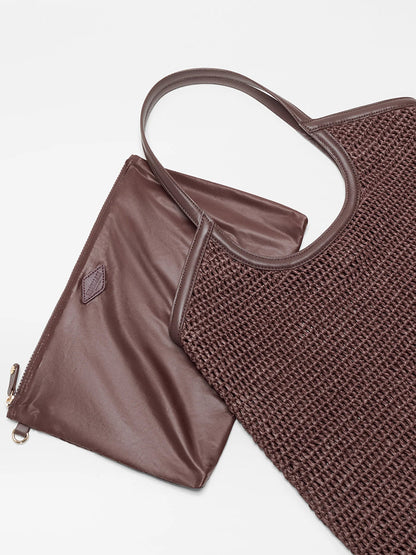The MZ Wallace Large Crochet Georgica Tote in Brown Crochet, with Italian leather handles and gold hardware, is displayed next to a matching brown leather zippered pouch on a white background.