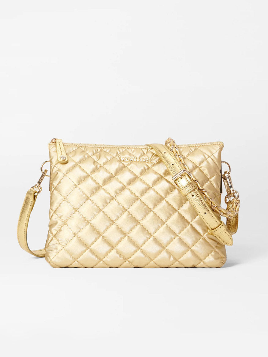 The MZ Wallace Large Crosby Pippa in Light Gold Pearl Metallic Oxford, featuring Italian leather trim, a matching adjustable strap, and a zipper closure, is displayed against a white background.