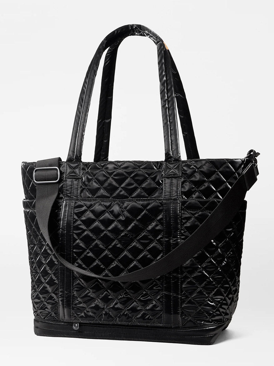 The MZ Wallace Large Empire Tote in Black Liquid Oxford is a stylish black quilted nylon tote bag featuring two short handles and an adjustable shoulder strap, making it perfect for those who love lightweight crossbody bags against a plain background.