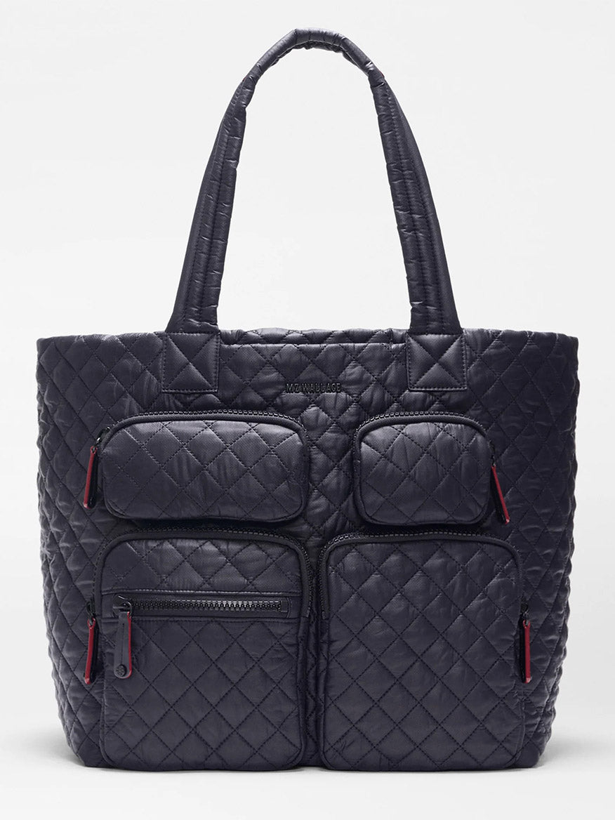 The MZ Wallace Large Metro Travel Tote in Black Oxford features a quilted design, Italian leather trim, two top handles, and four front zip pockets with red pulls—ideal as a stylish laptop bag.