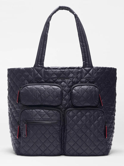 The MZ Wallace Large Metro Travel Tote in Black Oxford features a quilted design, Italian leather trim, two top handles, and four front zip pockets with red pulls—ideal as a stylish laptop bag.