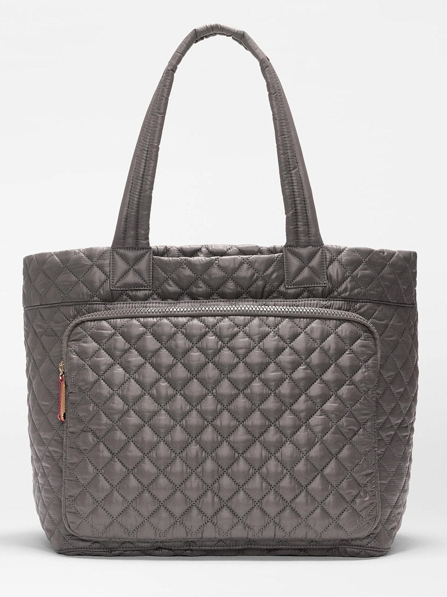 The MZ Wallace Large Metro Travel Tote in Magnet Oxford features a gray quilted design, two handles, and a front zippered pocket. Made from durable Oxford fabric, it is shown against a plain white background.