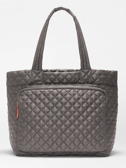 The MZ Wallace Large Metro Travel Tote in Magnet Oxford features a gray quilted design, two handles, and a front zippered pocket. Made from durable Oxford fabric, it is shown against a plain white background.