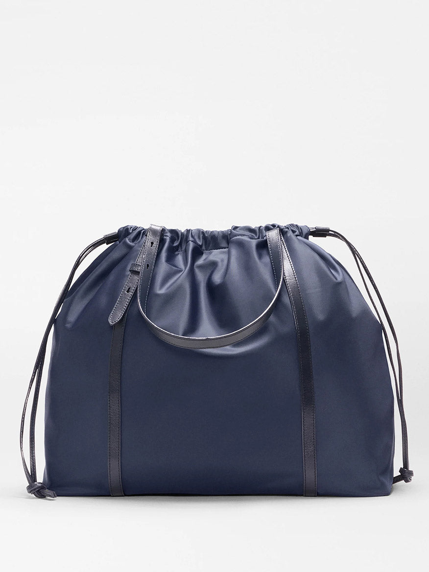 The MZ Wallace Large Waverly Tote in Dawn Bedford is a spacious navy tote with thin black Italian leather straps, a minimalist design, and fits a 15" laptop.