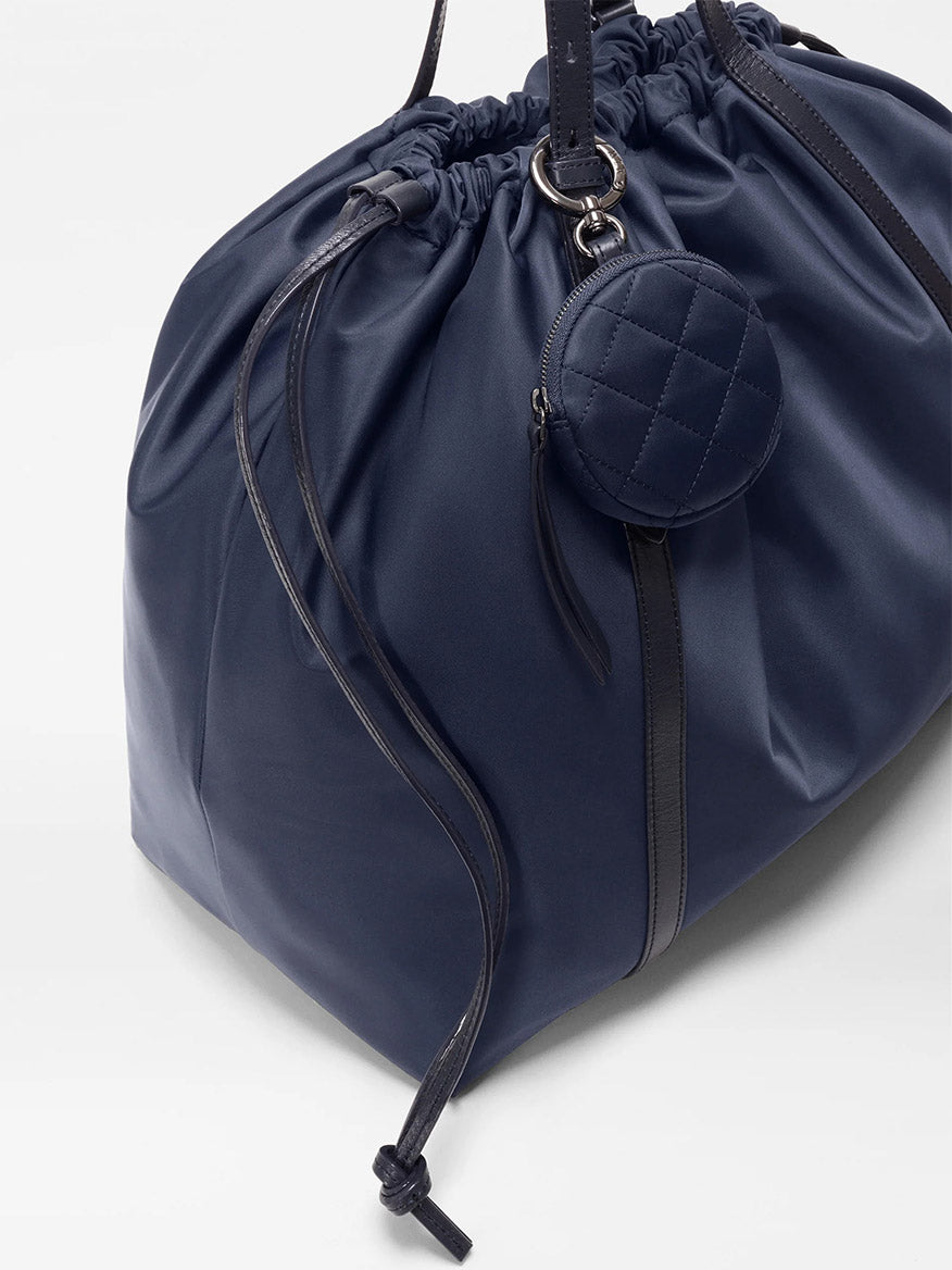 The MZ Wallace Large Waverly Tote in Dawn Bedford features a navy blue design with black Italian leather straps, a crossbody strap for versatility, and an attached small round quilted coin pouch.