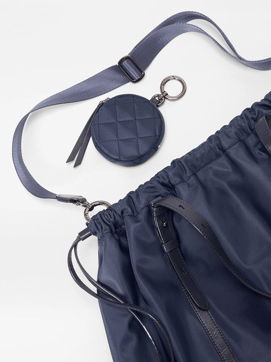 The MZ Wallace Large Waverly Tote in Dawn Bedford is a navy blue bag with Italian leather straps, a detachable quilted coin pouch, adjustable crossbody strap, and space for a 15" laptop, shown on a white background.