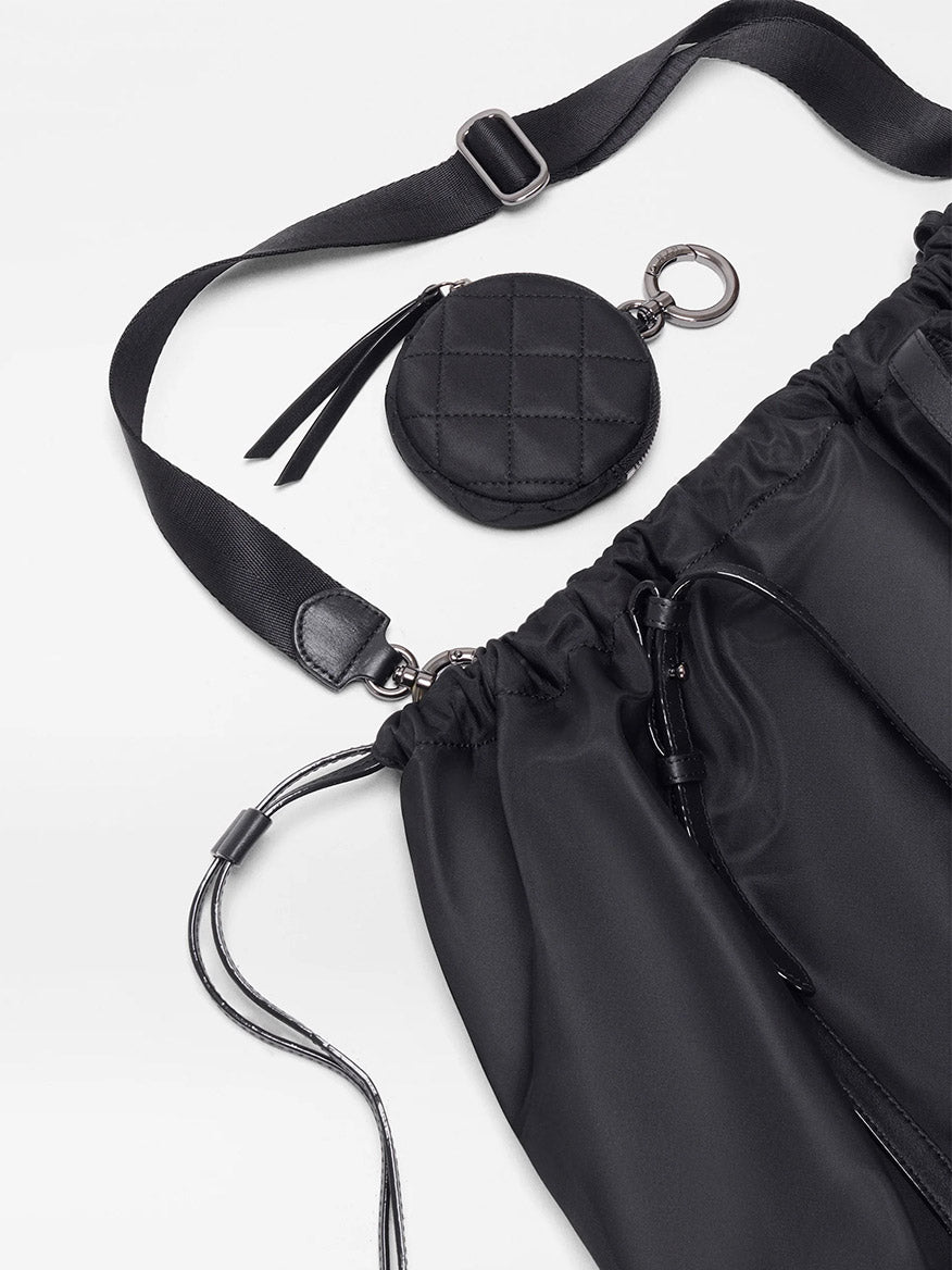 The MZ Wallace Large Waverly Tote in Black Bedford features a nylon crossbody strap, adjustable drawstring closure, and an attached round quilted coin pouch on a light background.