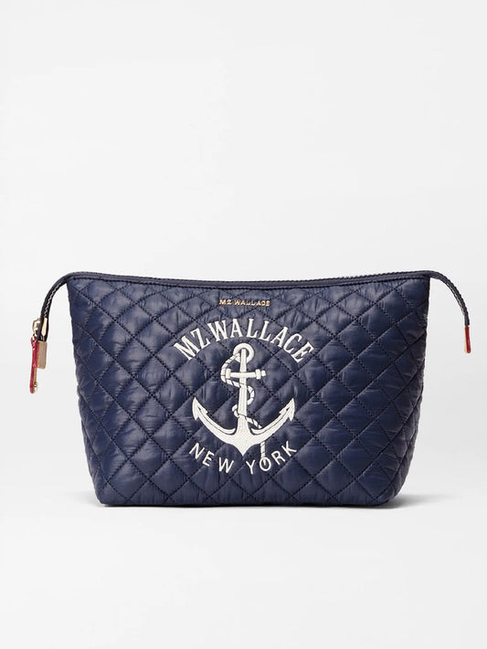 The MZ Wallace Large Zoey Cosmetic in Anchor Oxford is a navy blue quilted makeup pouch with a zipper, embroidered with "MZ Wallace New York" and an anchor—perfect for organizing your essentials in style while traveling.