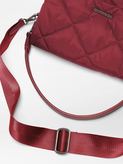 The MZ Wallace Madison Flap Crossbody in Claret Bedford, crafted from recycled Bedford nylon with a quilted design, features an adjustable strap and silver hardware, and is elegantly displayed on a white surface.
