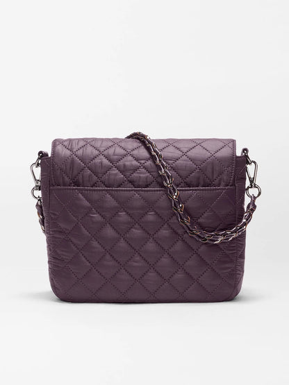 The MZ Wallace Crosby Lock Medium Crossbody in Raisin Oxford is a quilted, purple recycled nylon handbag featuring a flap closure and metal chain strap, elegantly accented with luxurious Italian leather trim, displayed against a plain white background.